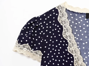 Detailed view of the navy polka dot fabric with intricate cream lace trim and stitching