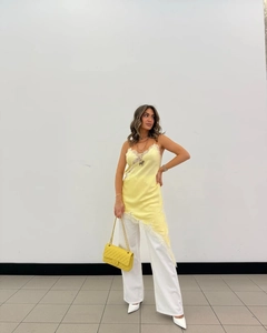 Detail of yellow satin camisole top with lace trim paired with white straight pants