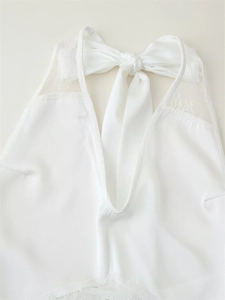 Detail of white lace patchwork halter dress with satin bow and delicate floral textures