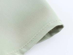 Detailed macro view of high-quality stitching and texture on sage green satin fabric