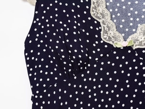 Detail of V-neckline with delicate lace trim and pink rose on navy polka dot dress