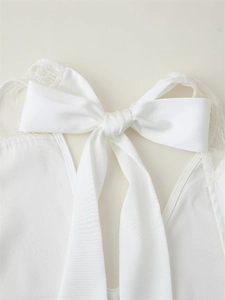 Detail of elegant white satin bow and delicate lace patchwork on the halter neck dress