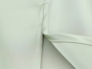 Detail shot of the fine stitching and silky mint green satin texture of the dress