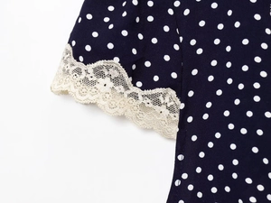 Detailed view of delicate lace patchwork on navy blue polka dot puff sleeve cuffs