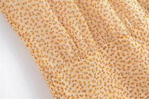 Dettaglio del tessuto floreale giallo con design a pieghe e cuciture di precisione
