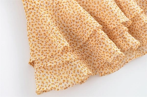 Dettaglio dell'abito in chiffon giallo a margherite con orlo a balze a tre strati