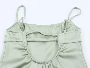 Detail of sage green satin backless dress with adjustable straps and pleated hemline