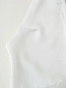 Detail of delicate white lace hem and smooth chiffon fabric on a halter fishtail dress