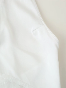 Detail of white dress showing elegant lace hemline and precise side dart stitching