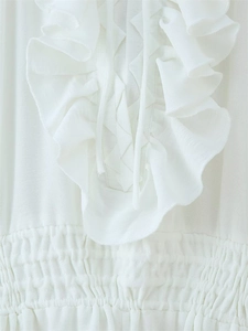 Detailansicht der Rüschenschichten und gesmokten Taille an einem weißen Maxikleid