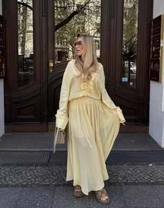 Detail von hellgelbem Volant-Langarmshirt und passendem fließendem Chiffon-Maxirock-Set