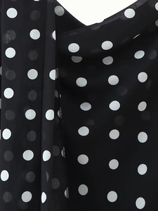 Detailed macro view of black chiffon fabric with classic white polka dot pattern print