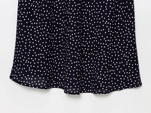 Detailed close-up of flowing black chiffon skirt hem with white polka dot print pattern
