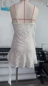 Détail de robe courte à paillettes blanches avec ourlet en mousseline et texture géométrique
