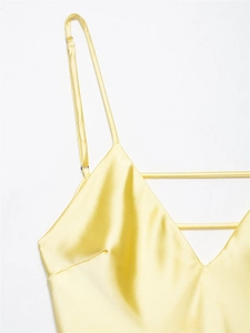 Detail of yellow satin midi dress featuring adjustable spaghetti straps and V-neckline