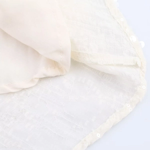 Détail de robe ivoire montrant la texture ondulée et les paillettes translucides