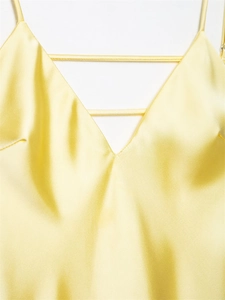 Detailed close-up of yellow satin midi dress featuring a deep V-neck and thin strap design