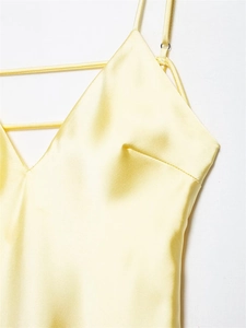 Close-up of light yellow satin dress showing delicate straps and smooth silk texture