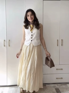 Détail d'une jupe longue plissée élégante avec un gilet blanc boutonné chic