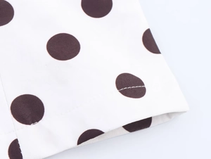 Close-up of neat hemline stitching and fabric texture on a polka dot camisole top