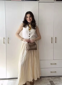 Détail du gilet blanc sans manches à boutons et jupe mi-longue plissée assortie