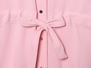 Detail of light pink shirt set showing golden metal buttons and waist ribbon bow