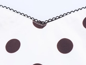 Close-up of V-neckline featuring black polka dots and delicate scallop lace trim