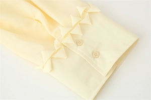 Makro-Detail von hellgelbem Chiffon-Ärmel mit Rüschen und zwei Harzknöpfen