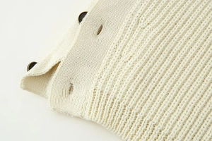 Detailed close-up of cream knit fabric showing thick vertical texture and black button