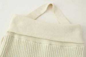 Close-up of cream knit halter top showing ribbed texture and fold-over neckline details