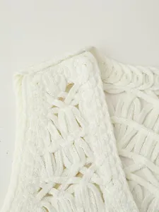 Macro shot of the white crochet vest showing intricate geometric hollow knit patterns