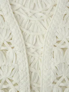 Close-up of white crochet vest featuring intricate hollow knit patterns and shell accents