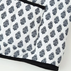 Detail of white quilted vest with blue floral print and black velvet-textured trim
