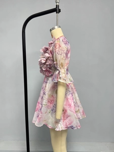 Détail d'une robe florale rose avec volants 3D et manches mi-longues à nœuds décoratifs