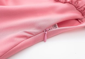Gros plan détaillé de la fermeture éclair invisible et de la texture plissée du top rose