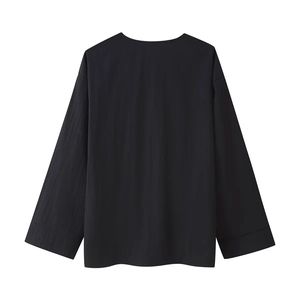 Détail du haut noir à manches longues montrant la texture lisse du tissu et la couture dos