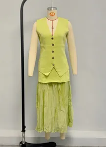 Détail du gilet en maille vert citron à boutons dorés et jupe longue plissée assortie
