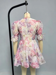 Détail d'une robe fleurie en mousseline avec manches bouffantes, rubans et zip au dos