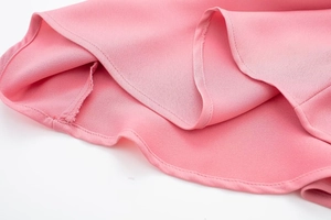 Vue détaillée de la texture du tissu crêpe rose et de la couture plate du bord