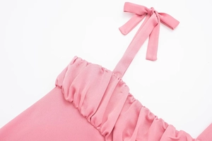 Détail du haut licou rose avec nœud papillon, plis froncés et texture de tissu tissé