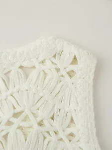 Close-up of white crochet vest featuring intricate hollow knit and seashell texture detail