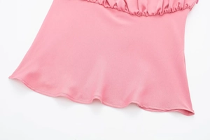 Détail de caraco rose plissé montrant le tissu en mousseline et les coutures soignées