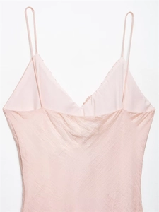 Detail of light pink silk slip dress with slim shoulder straps and deep V-neckline