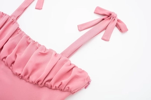 Détail du haut rose montrant la texture plissée, les nœuds et la fermeture éclair