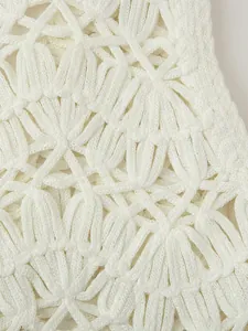 Macro shot of white crochet knit vest featuring detailed hollow shell-shaped patterns