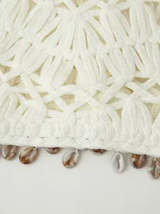 Detailed view of hollow crochet knit vest with natural shell charms on the hem