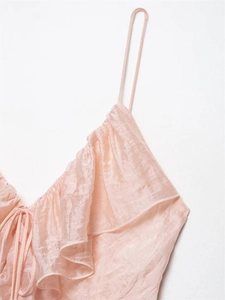 Close-up of the ruffled neckline and drawstring detail on the pink satin dress