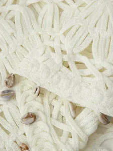Macro detail of bohemian hollow out knit vest with handcrafted seashell embellishments