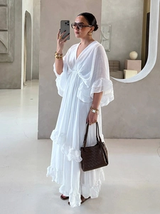 Dettaglio di un abito lungo bianco con scollo a V profondo e balze in stile bohémien