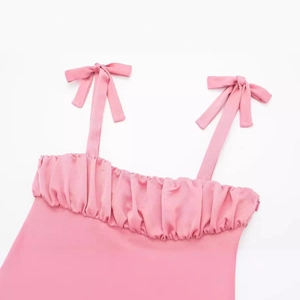 Haut caraco en satin rose avec bretelles à nœuds élégantes et décolleté plissé à volants